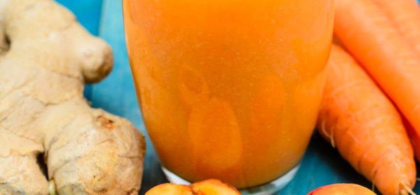 glass of apricot carrot juice on blue wooden table